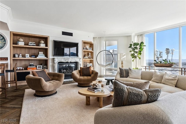 living room featuring crown molding, a fireplace, dark parquet floors, and built in shelves