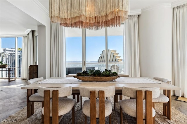 dining room with a water view, ornamental molding, wood-type flooring, and a wall of windows