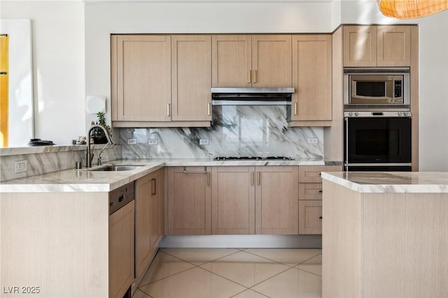 kitchen with appliances with stainless steel finishes, light brown cabinetry, sink, and decorative backsplash