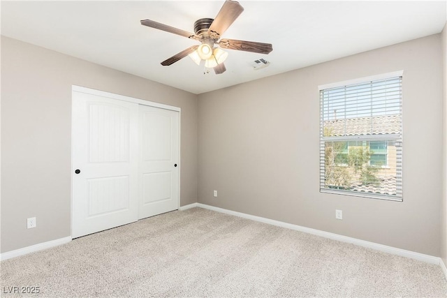 unfurnished bedroom featuring ceiling fan, light colored carpet, and a closet