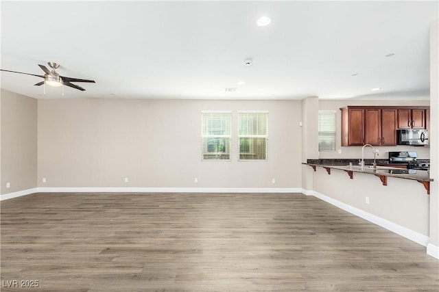 kitchen with wood-type flooring, stove, a breakfast bar area, and kitchen peninsula