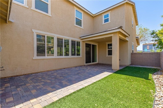 back of house with a patio area and a lawn