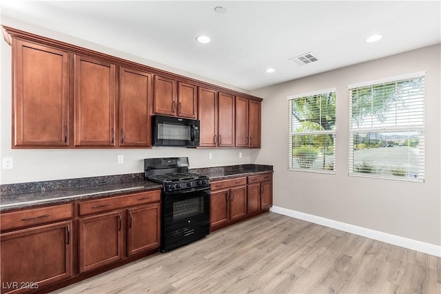 kitchen featuring black appliances, dark stone counters, and light wood-type flooring