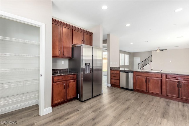 kitchen featuring dark stone countertops, stainless steel appliances, ceiling fan, and light wood-type flooring