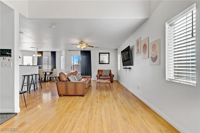 living room featuring wood-type flooring and ceiling fan with notable chandelier