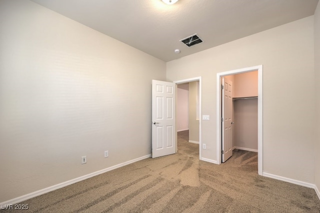 unfurnished bedroom with a walk in closet, carpet, and a closet