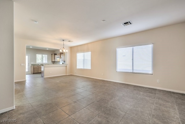 unfurnished living room with an inviting chandelier and tile patterned flooring