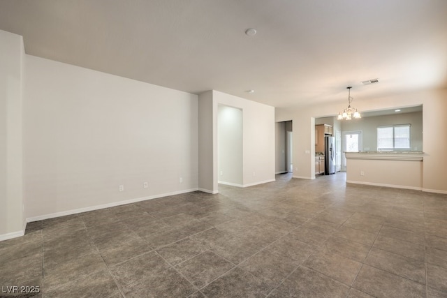 unfurnished living room featuring a chandelier