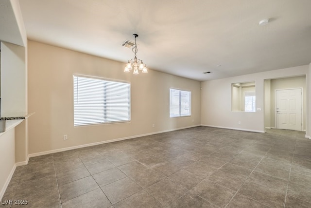 tiled spare room featuring a chandelier