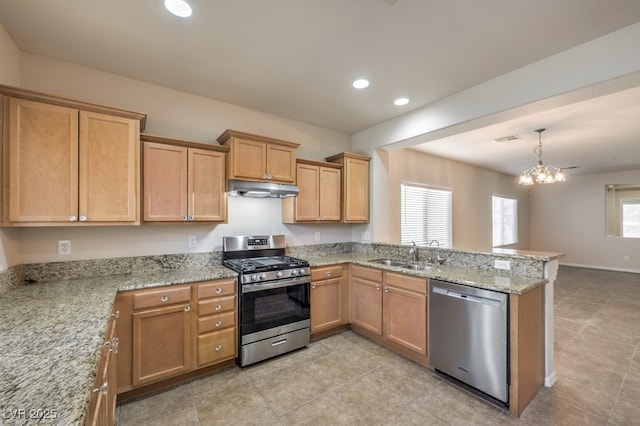 kitchen with sink, light stone counters, decorative light fixtures, appliances with stainless steel finishes, and kitchen peninsula