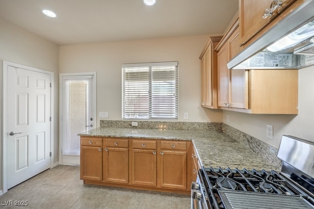 kitchen with stainless steel gas stove, light tile patterned floors, light stone counters, and ventilation hood