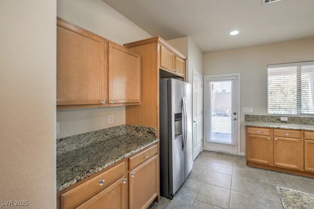 kitchen featuring light tile patterned flooring, stone countertops, and stainless steel fridge with ice dispenser