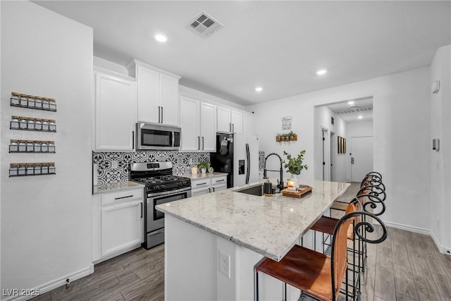 kitchen featuring white cabinetry, a breakfast bar area, stainless steel appliances, and an island with sink