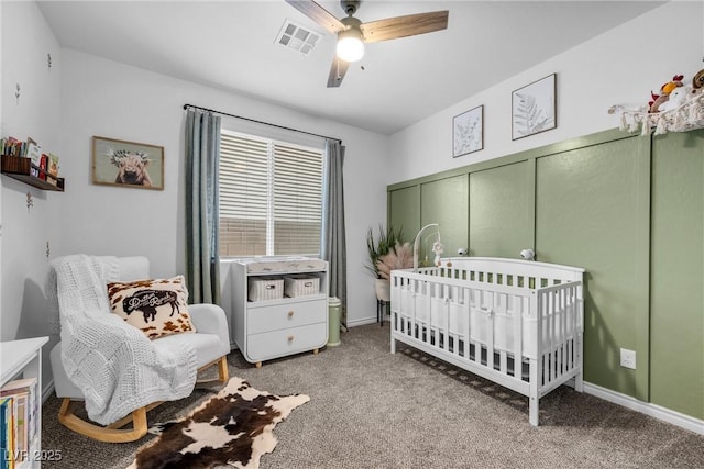 bedroom with a crib, ceiling fan, and carpet flooring