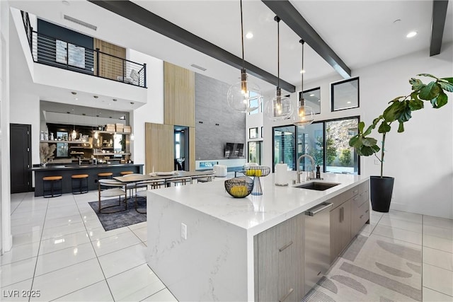 kitchen featuring sink, light stone counters, hanging light fixtures, dishwasher, and a large island