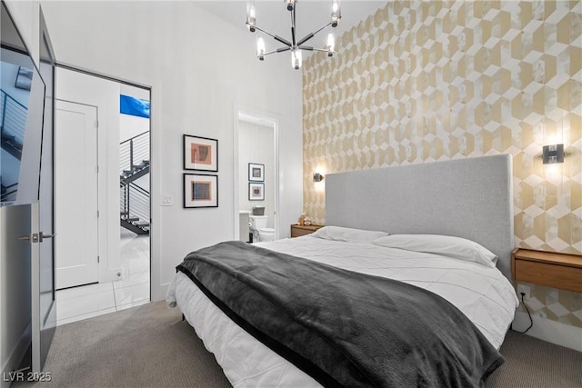 bedroom featuring ensuite bath, carpet floors, a chandelier, and a high ceiling