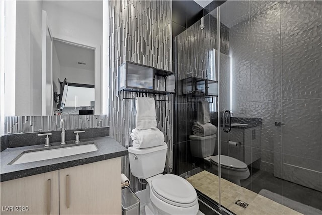 bathroom featuring vanity, toilet, and a shower with door