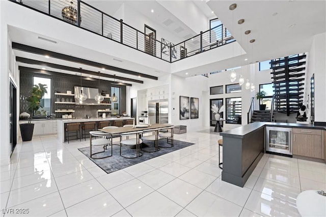 interior space with light tile patterned floors, a towering ceiling, and beverage cooler