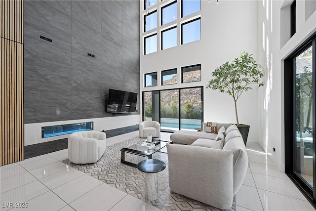 living room with a high ceiling, a wealth of natural light, and light tile patterned floors