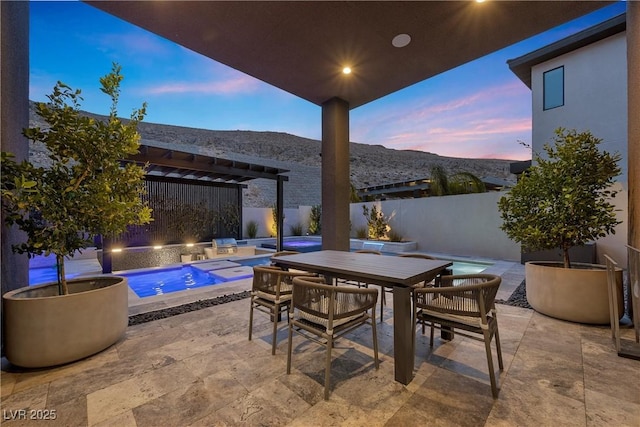 patio terrace at dusk featuring a fenced in pool, a mountain view, and a pergola