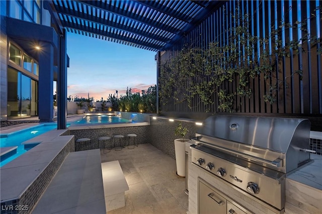 patio terrace at dusk with area for grilling and a pergola