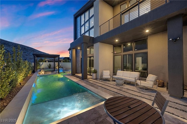 pool at dusk with pool water feature, an outdoor hangout area, a patio area, and a pergola