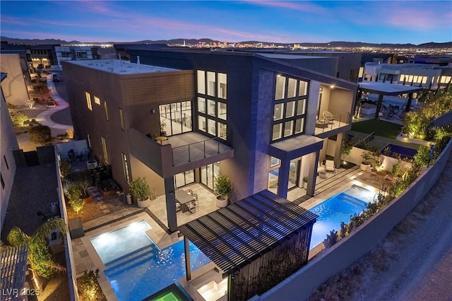 back house at dusk with a swimming pool with hot tub and a patio area