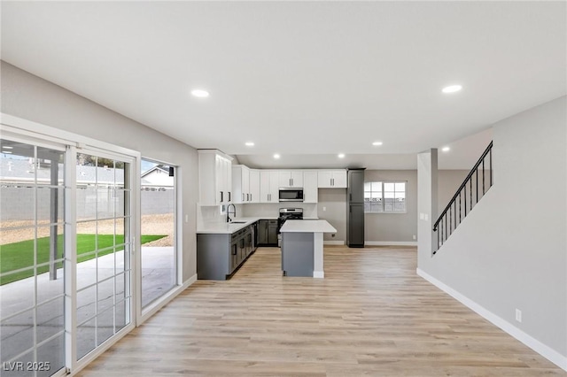 kitchen featuring a wealth of natural light, sink, a kitchen island, and white cabinets