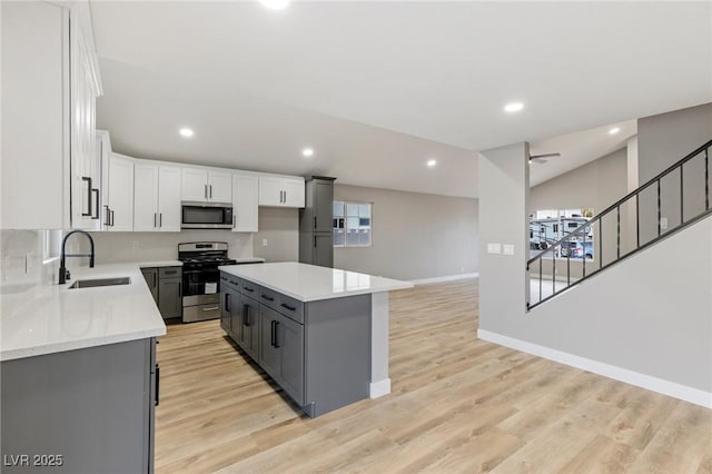 kitchen with sink, appliances with stainless steel finishes, light hardwood / wood-style floors, white cabinets, and a kitchen island