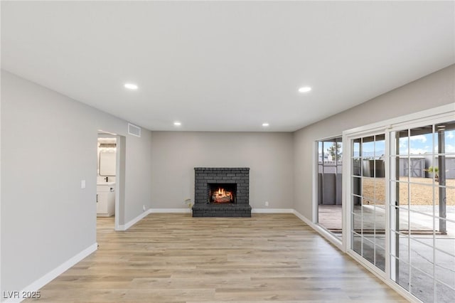 unfurnished living room with a brick fireplace and light wood-type flooring