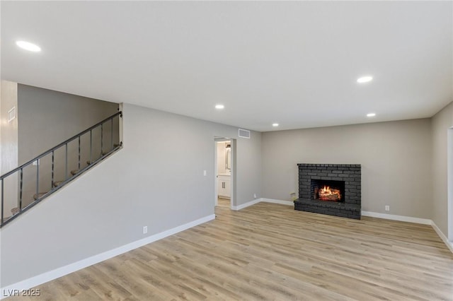 unfurnished living room with a brick fireplace and light hardwood / wood-style floors