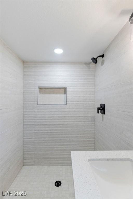 bathroom with tiled shower and sink