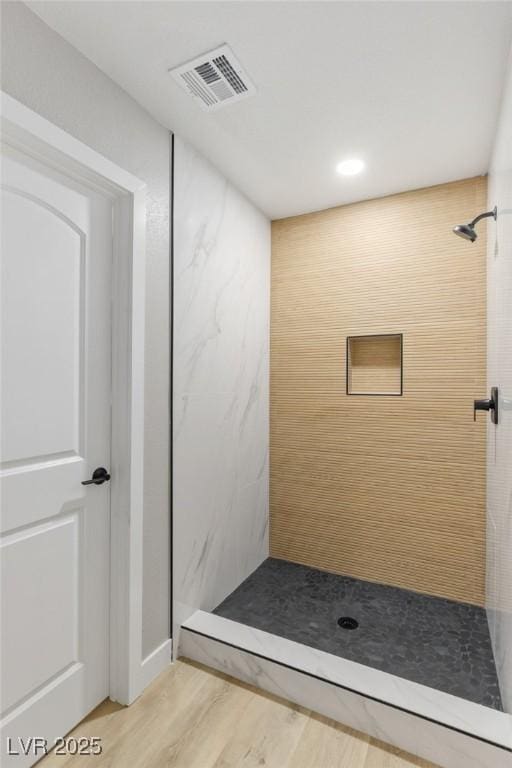 bathroom featuring a tile shower and hardwood / wood-style floors