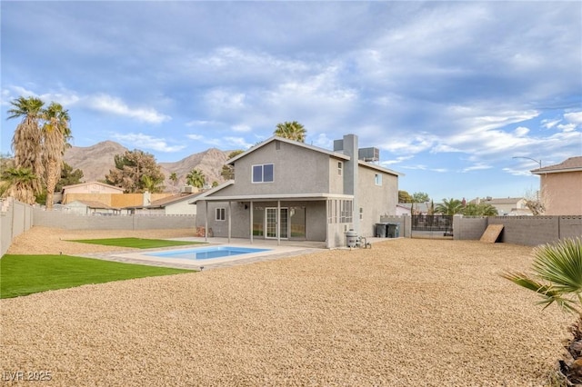 rear view of property featuring a mountain view, a patio area, and a fenced in pool