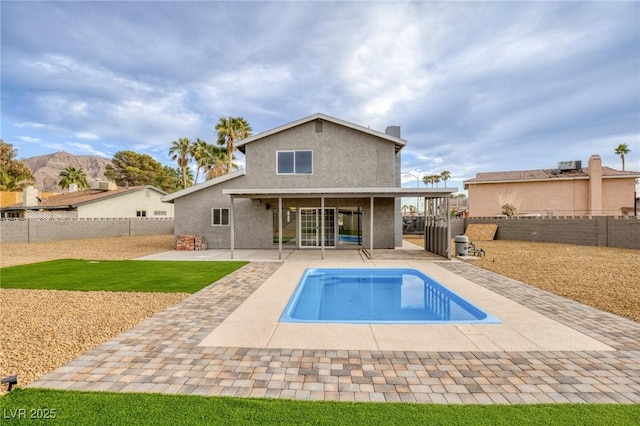 rear view of property featuring a fenced in pool, a patio, and a mountain view