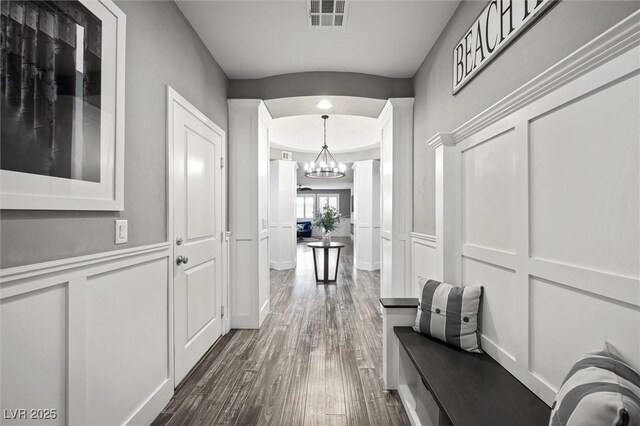 hall with dark hardwood / wood-style floors and an inviting chandelier