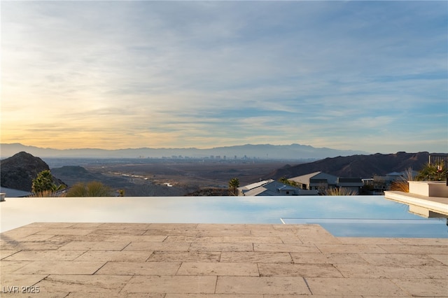 pool at dusk with a patio and a mountain view