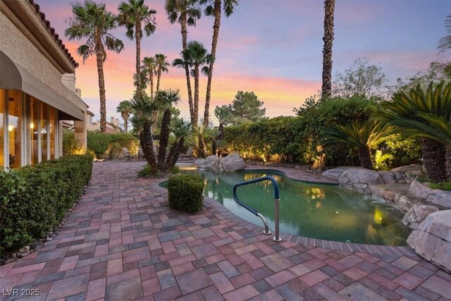 pool at dusk featuring a patio