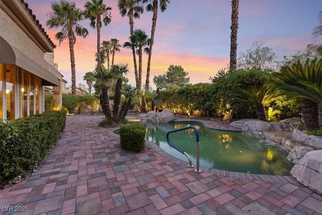 pool at dusk with a patio area