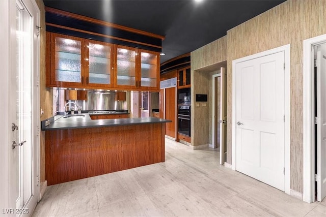 kitchen featuring sink, kitchen peninsula, and black appliances