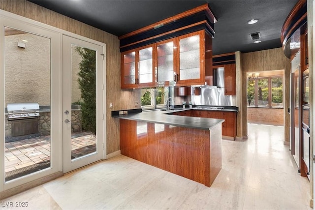 kitchen with stovetop, french doors, wall chimney range hood, sink, and kitchen peninsula