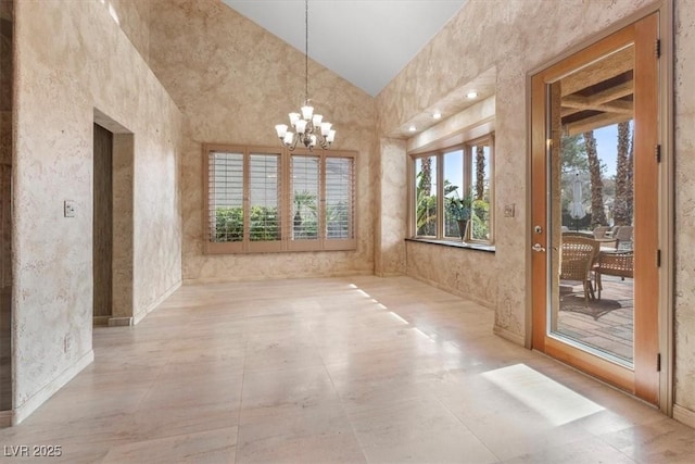 unfurnished dining area with high vaulted ceiling and an inviting chandelier