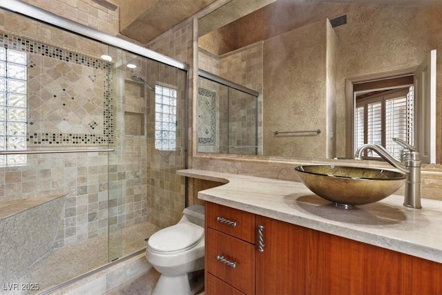 bathroom featuring vanity, a shower with door, and toilet