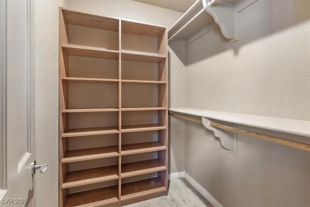 walk in closet with light hardwood / wood-style flooring