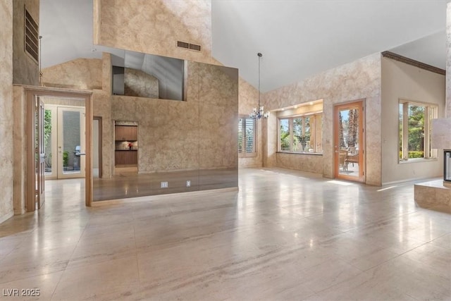 unfurnished living room featuring high vaulted ceiling, a chandelier, and a wealth of natural light