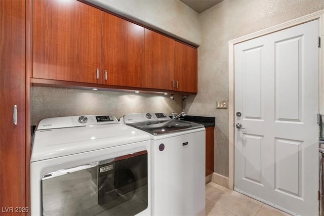 laundry room with light tile patterned floors, washer and dryer, and cabinets