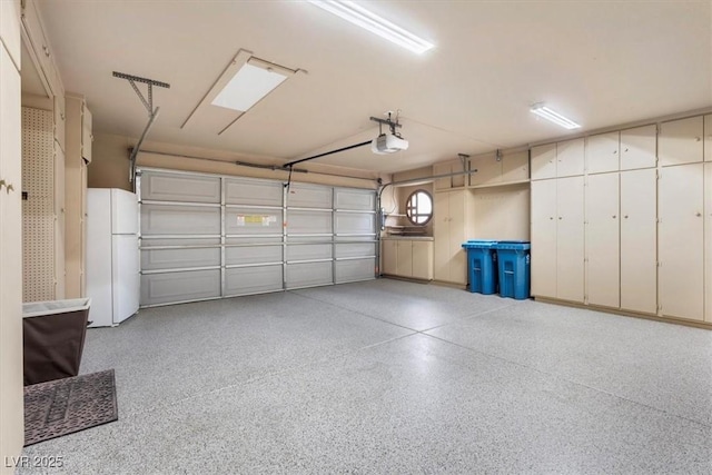 garage featuring white fridge and a garage door opener