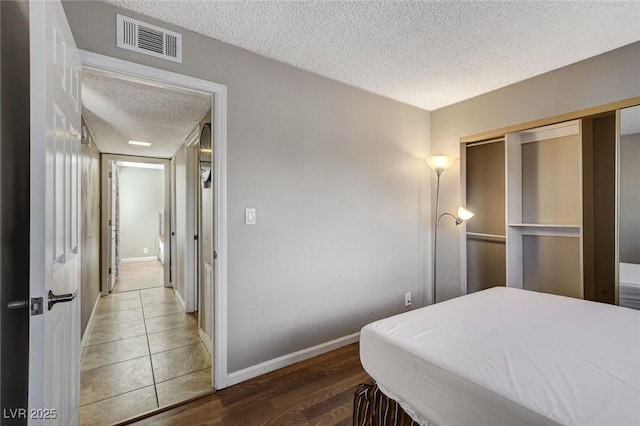 bedroom with dark wood-type flooring, a closet, and a textured ceiling