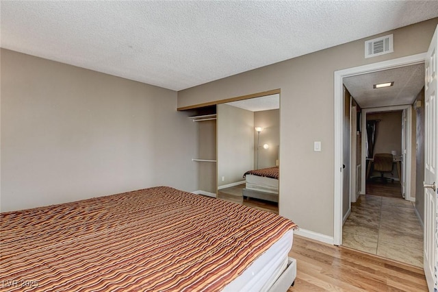 bedroom featuring a closet, a textured ceiling, and light hardwood / wood-style flooring