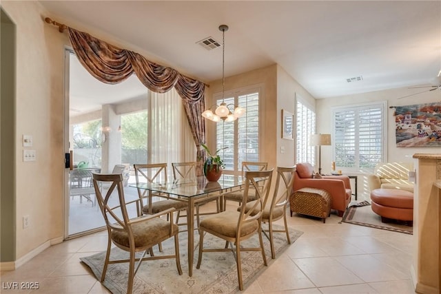 tiled dining space with ceiling fan with notable chandelier